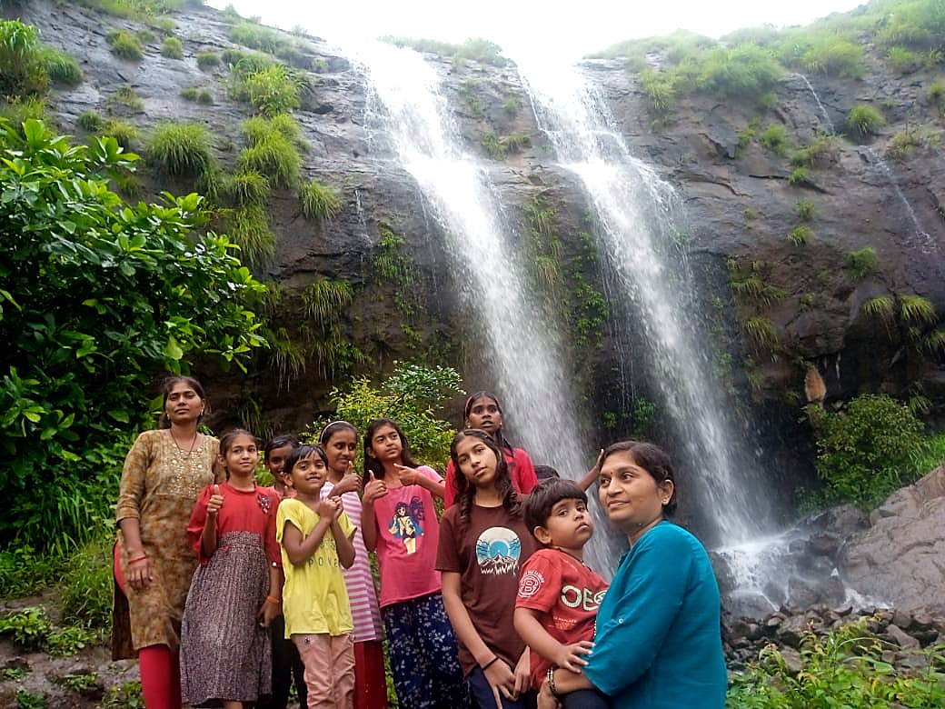 पावसाळी धबधब्यासमोर मुलांची सहल